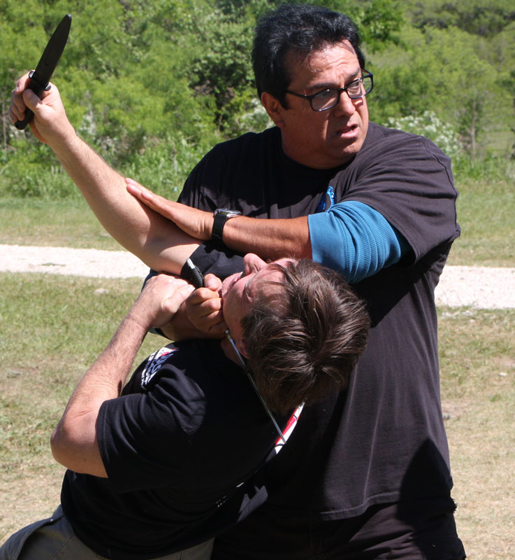 Master Corona demonstrating a knife defense technique with a student
